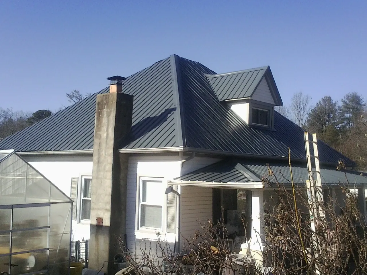 Dark blue standing seam metal roof on a white farmhouse with dormer — Slate & Tile Roof Repair by Roofing Brothers in Church Creek