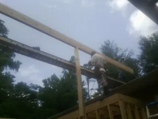 Carpenter setting a ridge beam over a new addition frame — Ice Dam Removal by Roofing Brothers in Church Creek