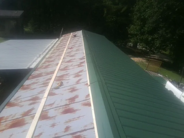 Old rusted panels beside newly installed green metal roofing — Wind Damage Roof Repair by Roofing Brothers in Church Creek