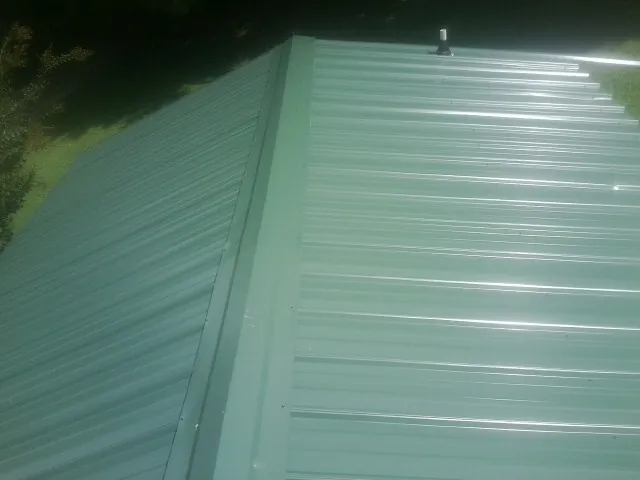 New green metal panels meeting at the ridge of a roof — Flat Roof Repair work by our crew in Church Creek