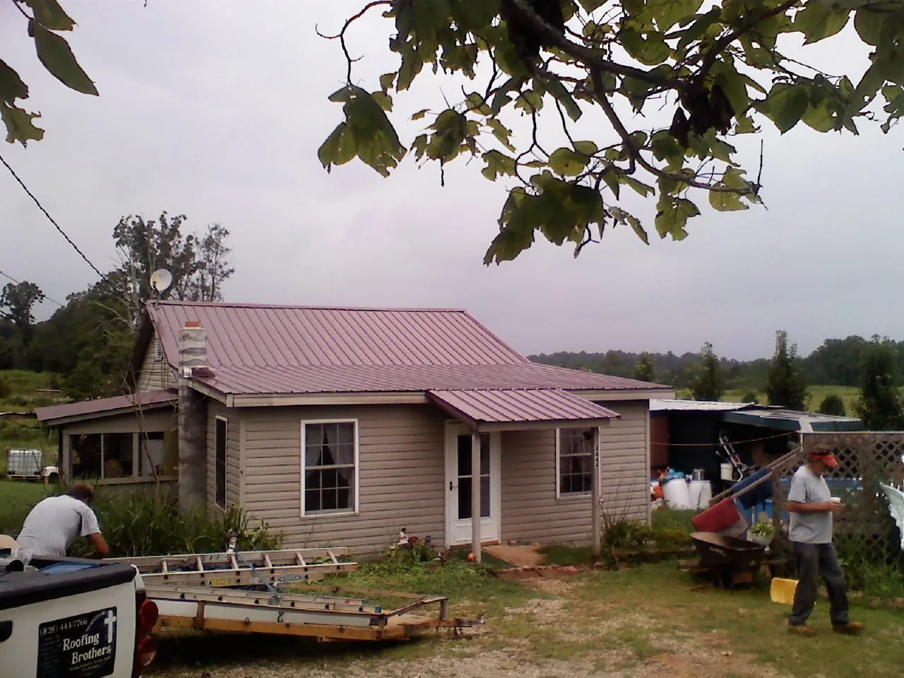 Crew finishing a mauve metal roof on a small farmhouse in Church Creek