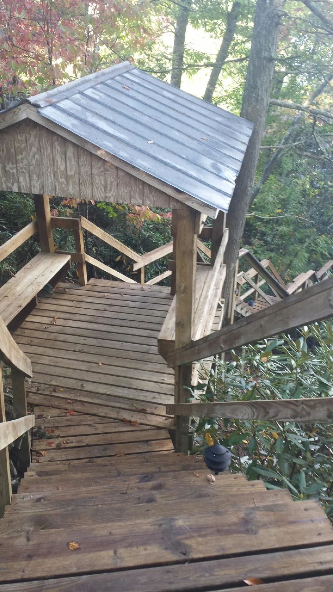 Metal roofed shelter over wooden steps on a wooded walkway — Skylight Repair & Installation work by our crew in Church Creek