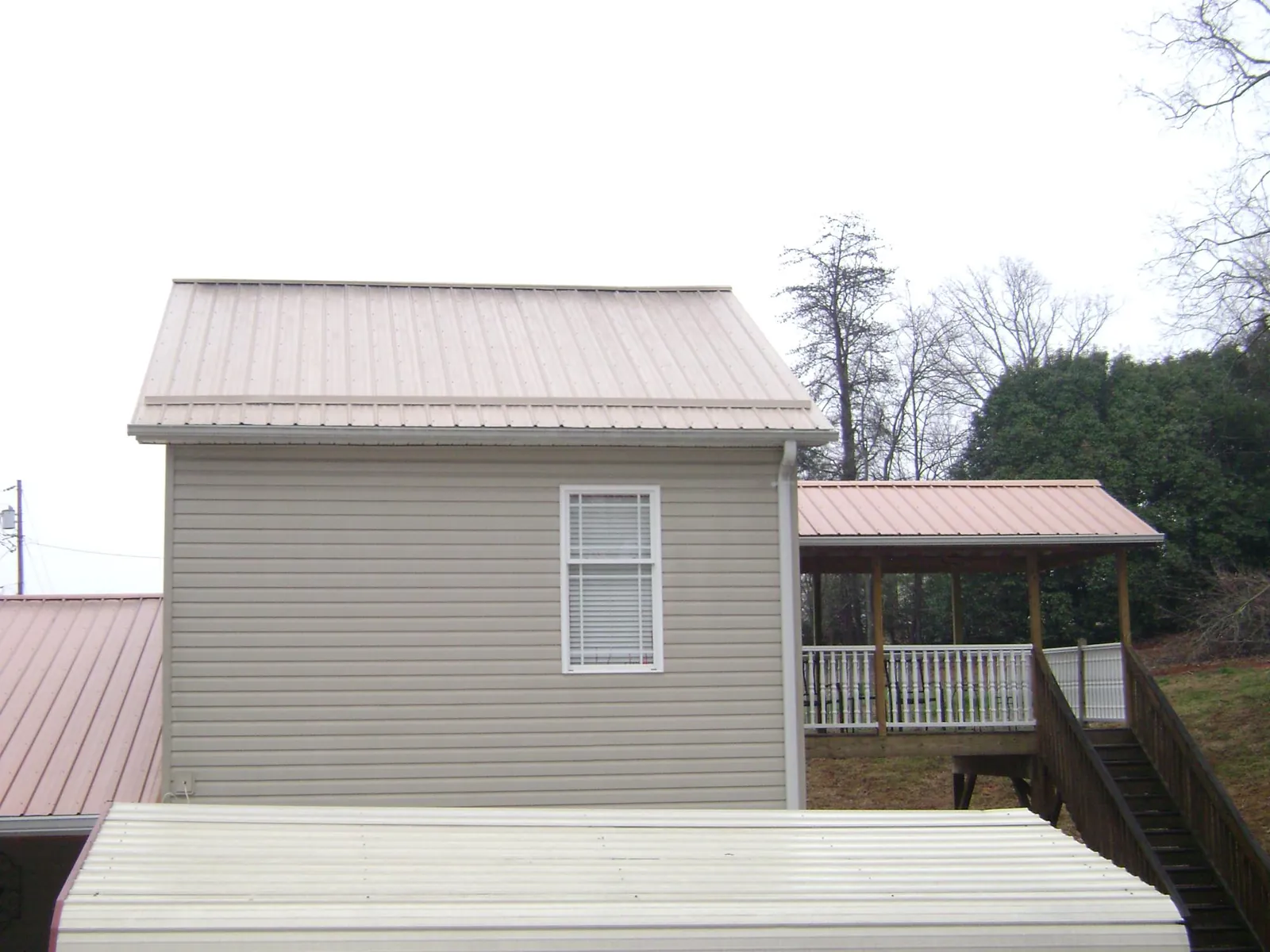 Tan metal roofs on a two story addition and attached porch, from a Roof Replacement job in Church Creek
