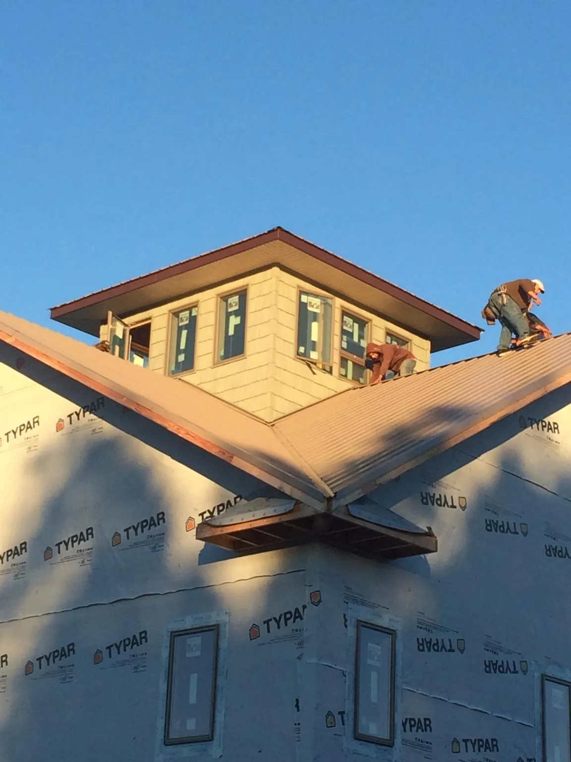 Roofers working around a rooftop cupola on a new metal roof at sunset — Roof Waterproofing in Church Creek by Roofing Brothers